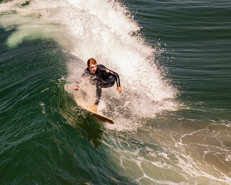 A surfer catching a wave at the Oceanside California pier. 